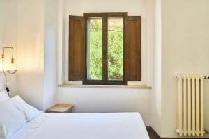 ein Schlafzimmer mit einem weißen Bett und einem Fenster in der Unterkunft Il Leccio Country House in Siena