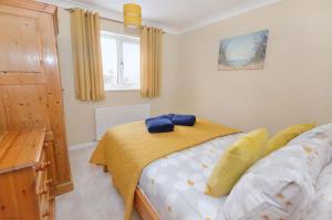 a bedroom with a bed with a yellow blanket at 18 Marriotts Way in Sheringham