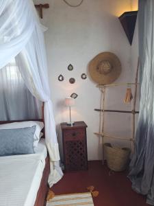 a bedroom with a bed and a table with a lamp at Pwani House - Lamu Seafront in Lamu