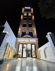 um grande edifício com uma torre de relógio à noite em lucky life hotel em Ấp Nhât (2)