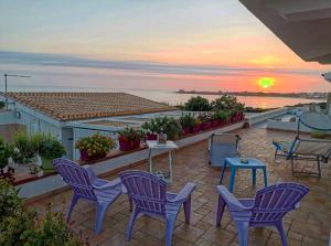 patio con sedie, tavolo e tramonto di TRAVELLIVING - Casa Vacanze Villa Ida, Beachfront a Punta Braccetto