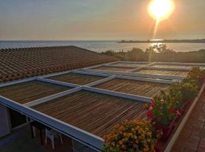 una fila di pannelli solari su un tetto con il tramonto di TRAVELLIVING - Casa Vacanze Villa Ida, Beachfront a Punta Braccetto