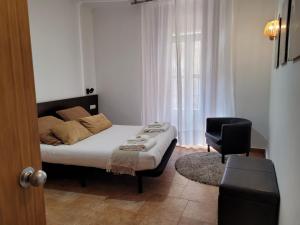 1 dormitorio con 1 cama, 1 silla y 1 ventana en Living Valencia Apartments - Merced, en Valencia