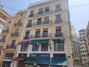 un edificio alto amarillo con un cartel en él en Living Valencia Apartments - Merced, en Valencia