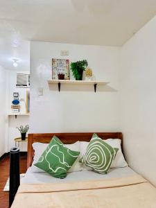 a bed with green and white pillows on it at Amancio's Balai - Near the Airport, City Center! in Puerto Princesa City