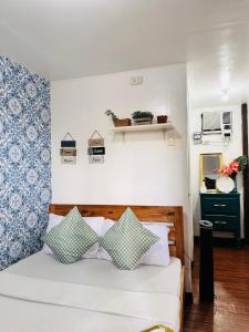 1 dormitorio con 1 cama con almohadas azules y blancas en Amancio's Balai - Near the Airport, City Center!, en Puerto Princesa City