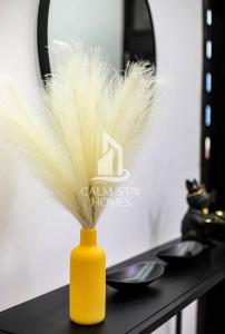 a yellow vase with feathers in it on a table at The Gray Haven Lakeside Condo in Entebbe