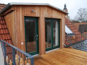 una casa de madera con puertas de cristal en una terraza en Ferien am Roten Haus, en Buckow