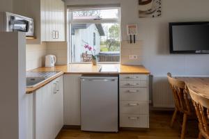 a kitchen with white cabinets and a sink and a table at South Central Country-Apartment in Brautarholt