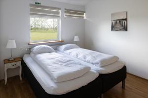 ein Bett mit vier Kissen in einem Schlafzimmer in der Unterkunft South Central Country-Apartment in Brautarholt