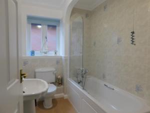 a bathroom with a toilet and a tub and a sink at Seaview Retreat in Sheringham