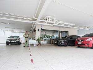 a man standing in a garage with several cars at Peaberry Place - พีเบอร์รี่เพลส in Ban Zong Katiam