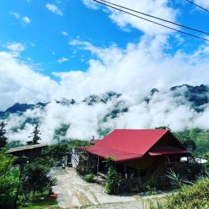 a building with a red roof in front of a mountain at Homestay Hoàng Vũ in Ha Giang
