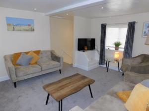a living room with a couch and a tv at St Christophers Cottage, Sheringham - Keys Holiday Cottages in Sheringham