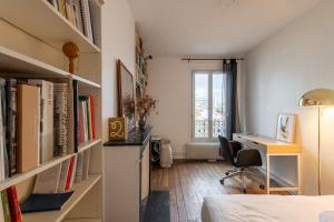 a room with a bed and a desk and bookshelves at Voltaire Cosy appartement au centre de Paris in Paris