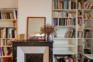 a mirror over a fireplace in a room with books at Voltaire Cosy appartement au centre de Paris in Paris