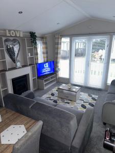 a living room with a couch and a tv at Presthaven sands P&Ts home from home in Talacre