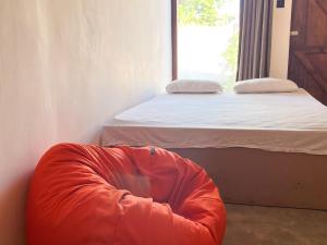 ein Schlafzimmer mit einem Bett und einem orangefarbenen Sitzsack in der Unterkunft Agastyā in Kataragama