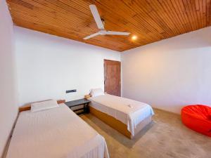 a bedroom with two beds and a ceiling fan at Agastyā in Kataragama