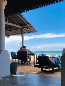 un grupo de personas sentadas en una mesa en la playa en Suite Lanka, en Hikkaduwa