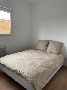łóżko w białym pokoju z oknem w obiekcie Les Chalets du Mancel - Chalet Victor - 500 m Bouleries Jump , 10 min du circuit des 24h w mieście Parence