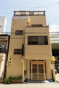 een bruin bakstenen gebouw met een hek aan de voorkant bij 大阪道顿堀 铁甲猫の家 in Osaka