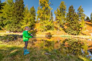 a young boy fishing in a pond at Galsterbergalm Jagdhütte in Auberg +3 photos