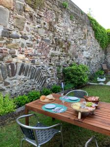 een houten tafel met borden eten erop naast een stenen muur bij De Stadswal in Maastricht