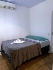 a bedroom with a bed with a gray blanket and blue pillows at Pousada Max House entre Praias de SFS in São Francisco do Sul