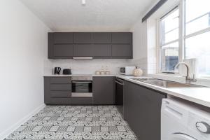 a kitchen with black cabinets and a sink at The Camden Road Collection in London