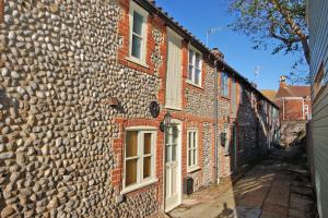 an old stone building with a stone wall at 2 Museum Cottages in Sheringham
