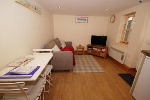 a living room with a couch and a television at 2 Museum Cottages in Sheringham