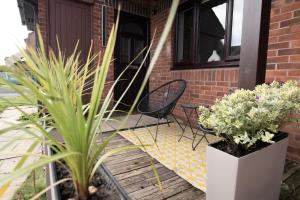 a porch with two chairs and potted plants on it at Dorset Stylish Apartment in Poole