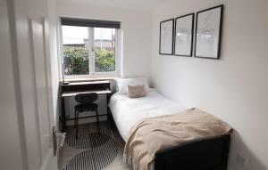 a bedroom with a bed and a desk and a window at Dorset Stylish Apartment in Poole