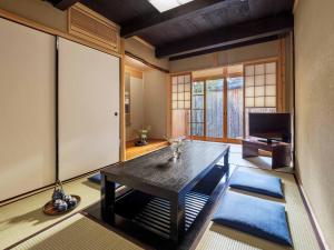 uma sala de estar com uma mesa e uma televisão em Sumire-an Machiya House em Quioto