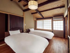 two beds in a room with wooden ceilings and windows at Sumire-an Machiya House in Kyoto