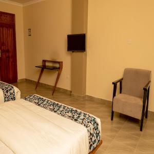 a bedroom with a bed and a chair and a tv at Star View Hotel Restaurant and Bar in Kampala