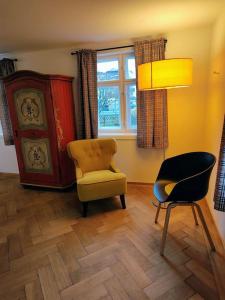 a living room with a chair and a table and a lamp at Ferienwohnung RESL - geschmackvoll renoviert & zentral im historischen Schindelhaus in Oberstaufen