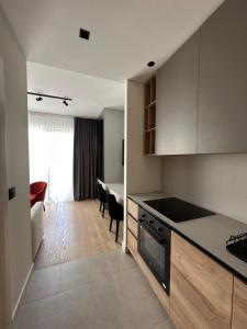 a kitchen with white cabinets and a living room at BW Lux Apartments in Sajmište