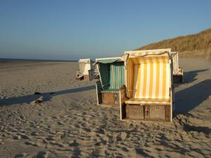 uma fila de cadeiras de praia sentadas na praia em Naturhotel Baltrum em Baltrum