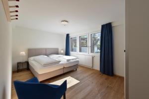ein Schlafzimmer mit einem Bett und einem blauen Stuhl in der Unterkunft Ferienlenk Mountain Village in Lenk im Simmental