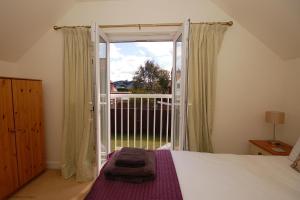 a bedroom with a bed and a large sliding glass door at 2 Old Dairy Court in Sheringham