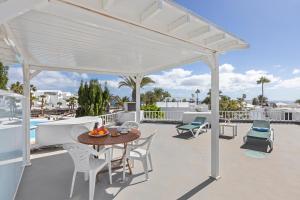 a white pergola on a patio with a table and chairs at Villa Devi in Costa Teguise
