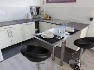 a kitchen with a table and two stools in it at Studio loué entier proche de Paris in Ecquevilly