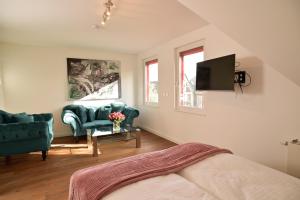 Una sala de estar con un sofá y sillas y un televisor. en Victoria Boardinghouse, en Düsseldorf