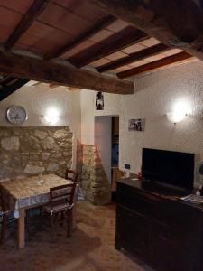 Habitación con mesa, TV y pared de piedra. en Casale le Piagge en Roccastrada