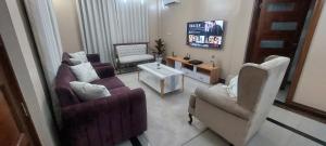ein Wohnzimmer mit Sofas und Stühlen sowie einem TV in der Unterkunft Sami BnB - Apt 01 Makongo after Mlimani City in Daressalam