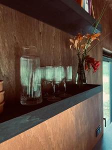 Eine Reihe Gläser auf einer Theke, dazu Blumen in einer Vase in der Unterkunft Bento Houses Domki w lesie, cisza pod Warszawą in Kąck + 18 Fotos