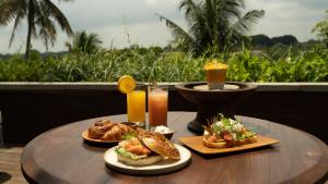 a wooden table with two plates of food and drinks at The Ridge Bali in Ubud