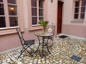 2 chaises et une table avec un vase sur la terrasse dans l'établissement Urgemütliches Apartment im Denkmal, à Halle-sur-Saale